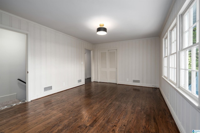 spare room with ornamental molding, dark wood-type flooring, and visible vents