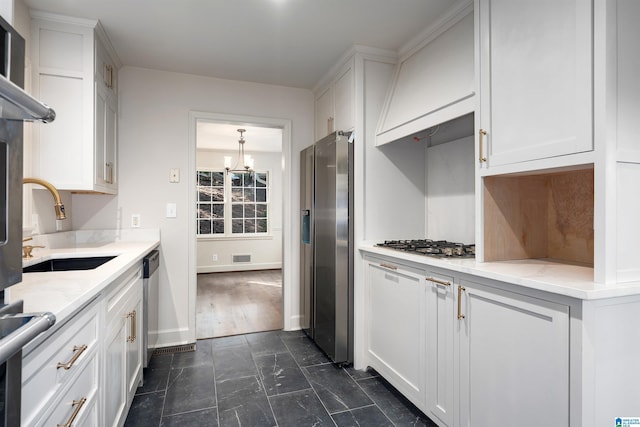 177 Ross Dr, Mountain Brook, AL 35213 - kitchen with stainless steel appliances, a chandelier, a sink, and white cabinetry