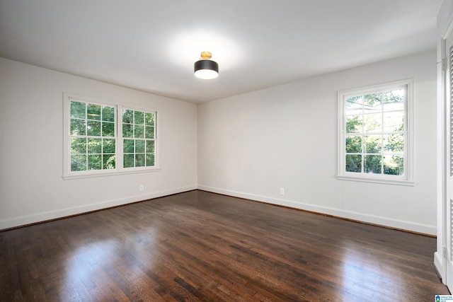 empty room with dark wood-type flooring and baseboards