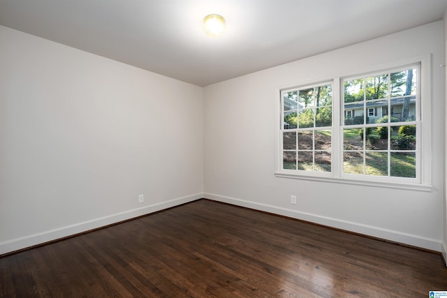 unfurnished room featuring baseboards and dark wood-type flooring