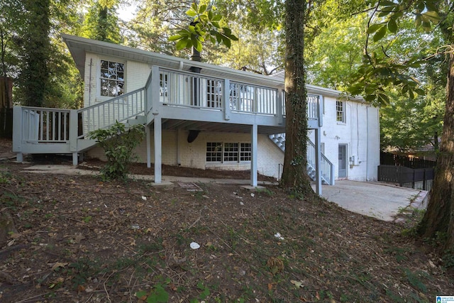 rear view of house with a deck, brick siding, and stairway