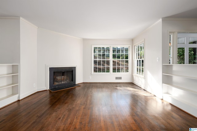 unfurnished living room with crown molding, visible vents, a fireplace with raised hearth, dark wood-type flooring, and baseboards