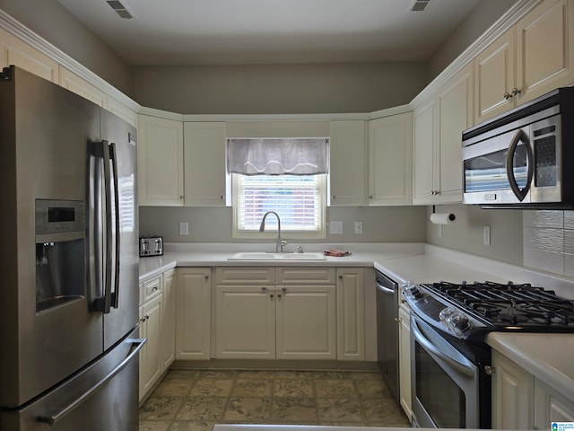 kitchen featuring appliances with stainless steel finishes, white cabinetry, and sink