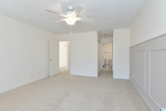 spare room featuring light carpet, a textured ceiling, and ceiling fan