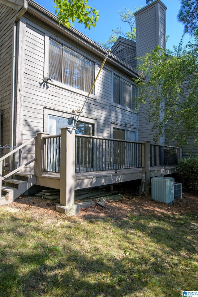 back of property with a wooden deck, a lawn, and central air condition unit