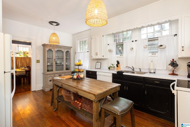 kitchen featuring dark hardwood / wood-style flooring, white appliances, sink, white cabinetry, and hanging light fixtures