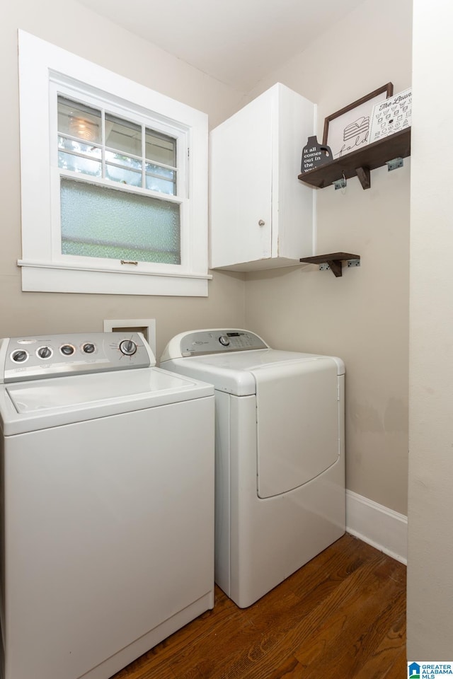 clothes washing area featuring washing machine and clothes dryer, dark wood-type flooring, and cabinets