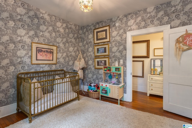 bedroom featuring a chandelier, wood-type flooring, and a crib