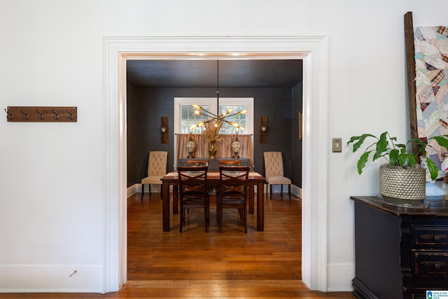 dining area featuring dark hardwood / wood-style flooring and an inviting chandelier