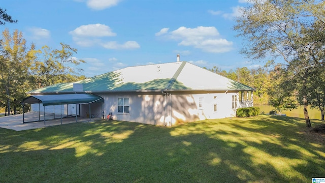 rear view of house with a lawn and a carport