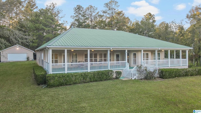 farmhouse-style home with a front yard, a porch, an outbuilding, and a garage