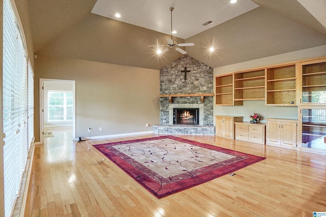 living room featuring light hardwood / wood-style floors, a stone fireplace, high vaulted ceiling, and ceiling fan