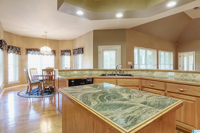 kitchen with black dishwasher, sink, a center island, light hardwood / wood-style floors, and tasteful backsplash