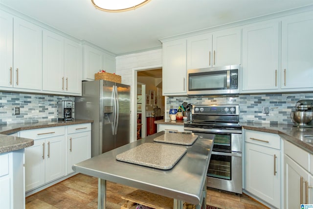 kitchen featuring appliances with stainless steel finishes, white cabinetry, light wood-type flooring, and backsplash