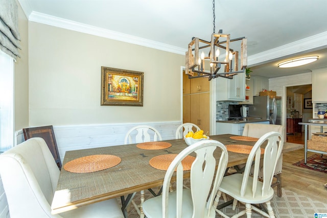 dining area with an inviting chandelier, ornamental molding, and light wood-type flooring