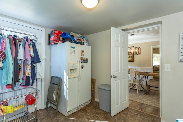 kitchen featuring white fridge with ice dispenser, ornamental molding, and a chandelier