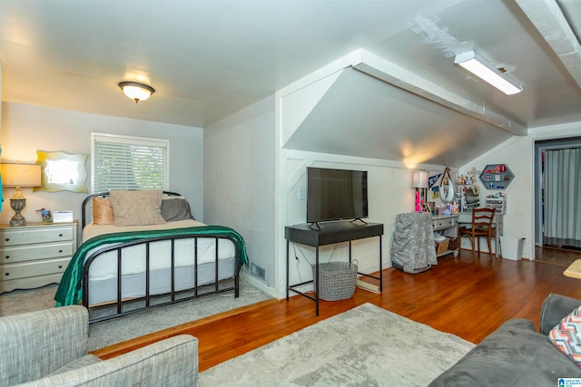 bedroom featuring hardwood / wood-style floors and vaulted ceiling with beams