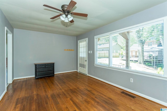 unfurnished room featuring dark wood-type flooring and ceiling fan