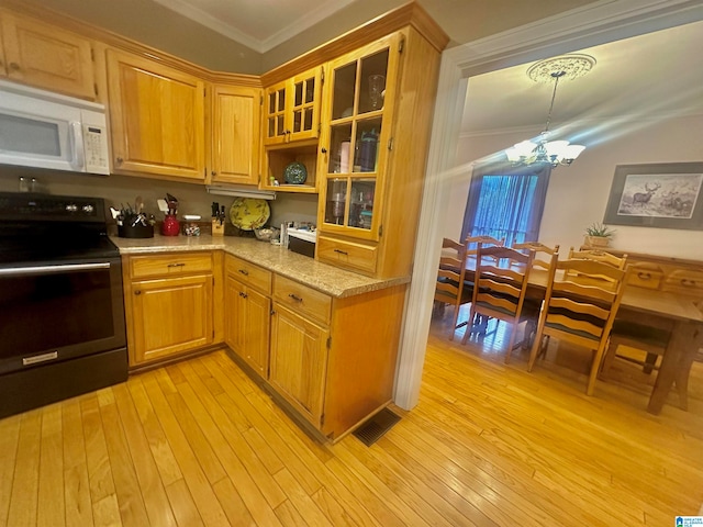 kitchen featuring light wood-type flooring, ornamental molding, a chandelier, electric range, and light stone countertops