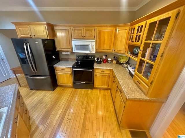 kitchen featuring light stone countertops, stainless steel fridge, light hardwood / wood-style floors, crown molding, and black / electric stove