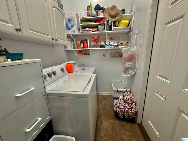 laundry room featuring washer and dryer, dark tile patterned floors, and cabinets