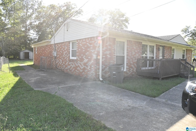 view of home's exterior featuring a shed, a deck, and a lawn