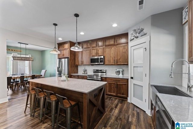 kitchen featuring dark hardwood / wood-style floors, hanging light fixtures, stainless steel appliances, sink, and tasteful backsplash