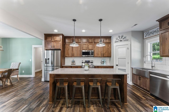 kitchen featuring dark hardwood / wood-style floors, appliances with stainless steel finishes, pendant lighting, and a kitchen island