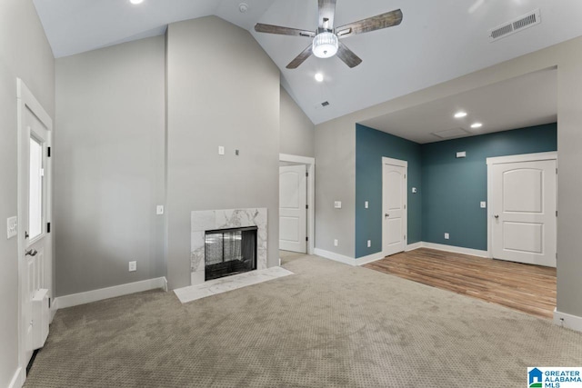 unfurnished living room featuring a high end fireplace, ceiling fan, high vaulted ceiling, and carpet floors