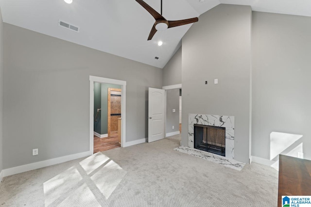 unfurnished living room with light carpet, a premium fireplace, high vaulted ceiling, and ceiling fan