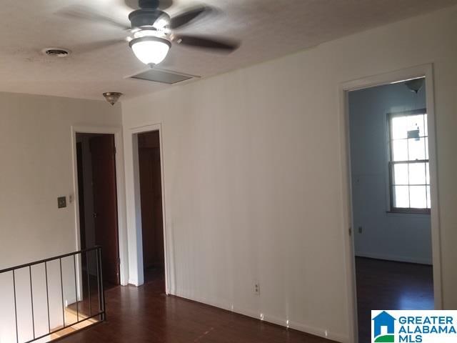 empty room featuring dark wood-type flooring and ceiling fan