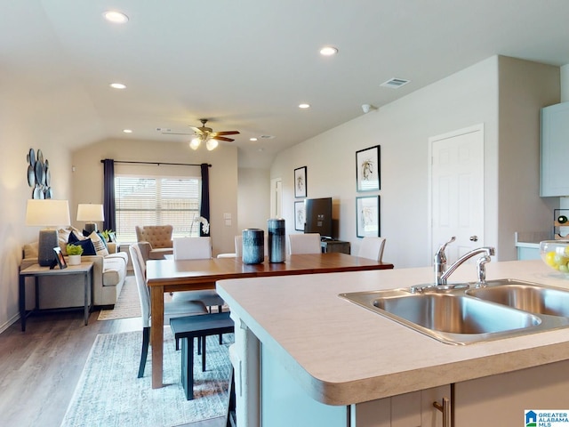 kitchen with ceiling fan, sink, light wood-type flooring, and a kitchen island with sink