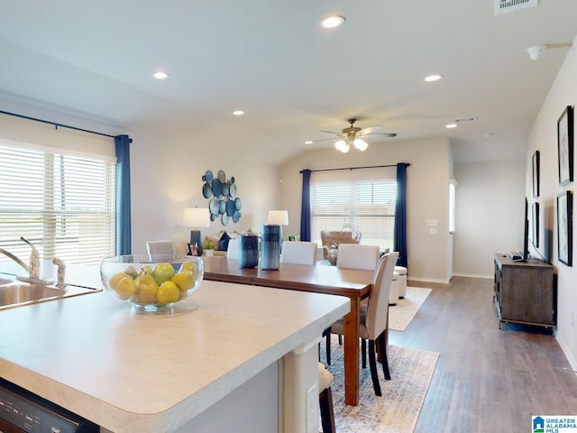 kitchen featuring dishwasher, lofted ceiling, sink, hardwood / wood-style flooring, and a kitchen island