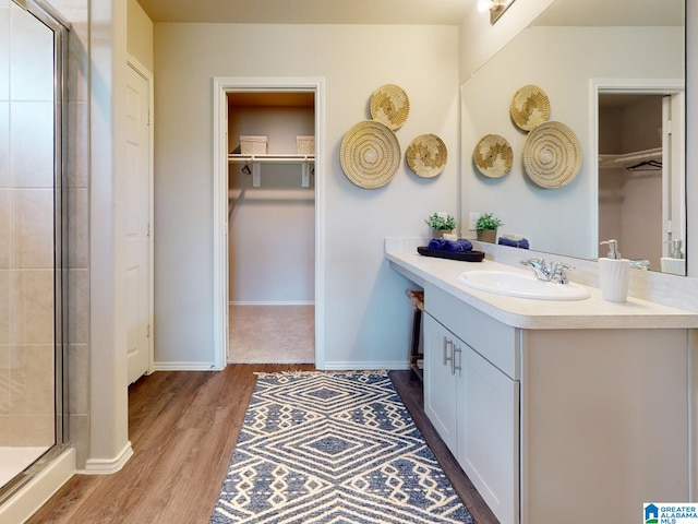 bathroom with wood-type flooring, vanity, and an enclosed shower