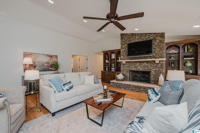 living room with lofted ceiling, a fireplace, light wood-type flooring, and ceiling fan