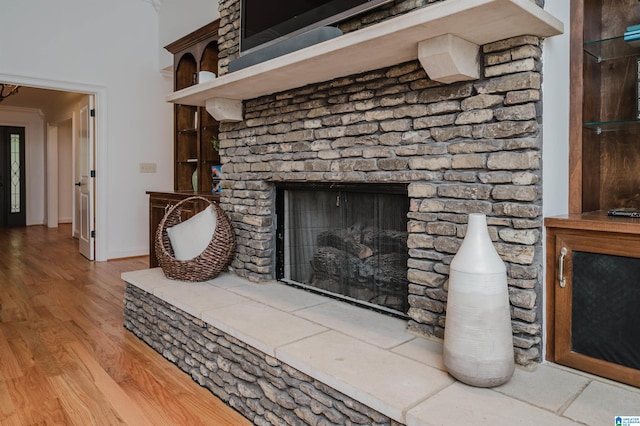 interior details with a large fireplace, ornamental molding, and hardwood / wood-style floors