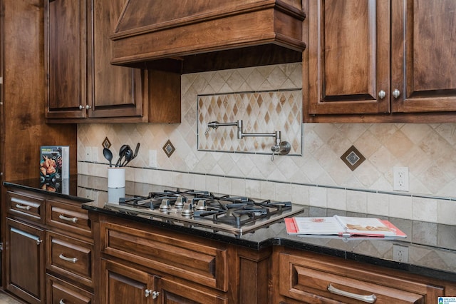 kitchen with custom exhaust hood, decorative backsplash, dark stone countertops, and stainless steel gas stovetop