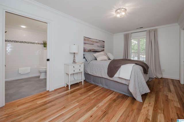 bedroom featuring light hardwood / wood-style floors, crown molding, and ensuite bathroom