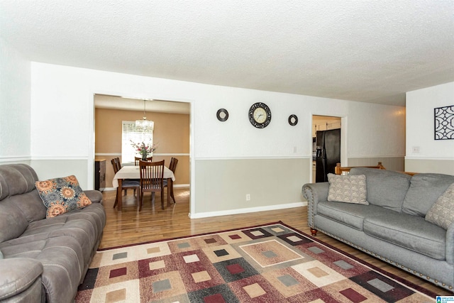 living room with a notable chandelier, a textured ceiling, and hardwood / wood-style flooring