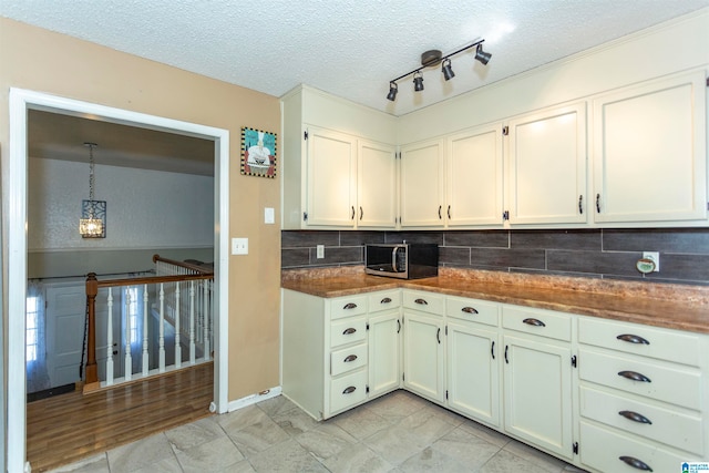 kitchen with decorative backsplash, track lighting, decorative light fixtures, white cabinetry, and a textured ceiling