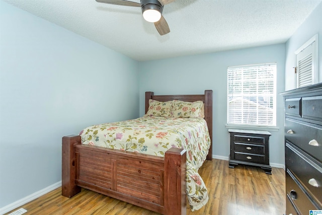 bedroom with ceiling fan, a textured ceiling, and hardwood / wood-style floors