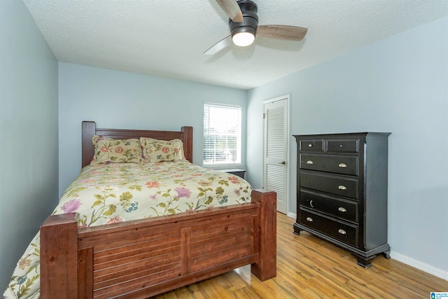 bedroom with light hardwood / wood-style flooring, a textured ceiling, a closet, and ceiling fan