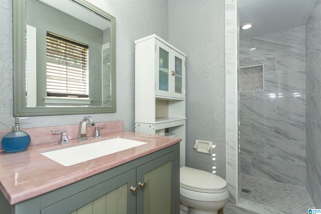 bathroom featuring vanity, toilet, and a tile shower