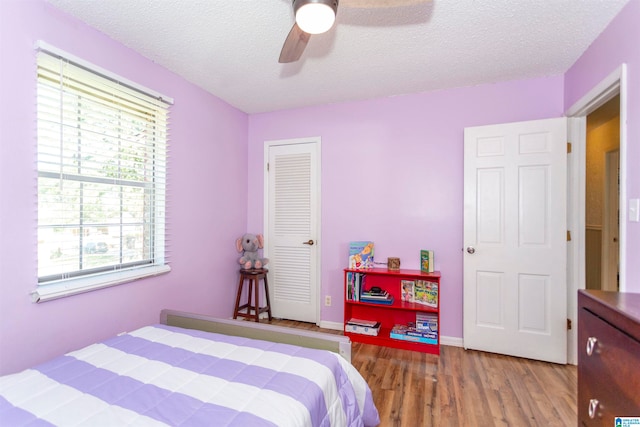 bedroom featuring a textured ceiling, wood-type flooring, a closet, and ceiling fan