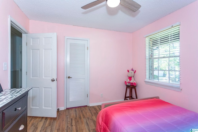 bedroom featuring a closet, ceiling fan, a textured ceiling, and dark hardwood / wood-style floors