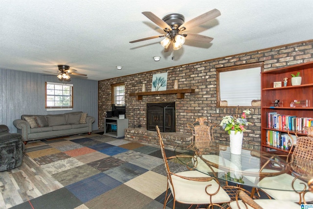 living room with dark wood-type flooring, ceiling fan, brick wall, and a textured ceiling