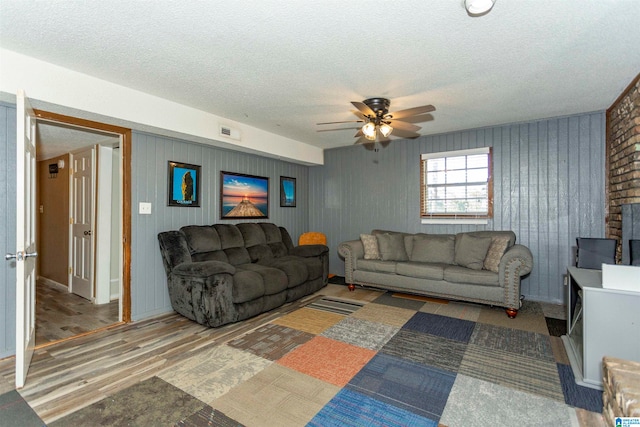 living room with hardwood / wood-style floors, a textured ceiling, and ceiling fan