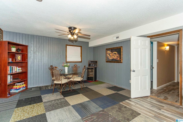 dining area with ceiling fan, a textured ceiling, and dark hardwood / wood-style flooring