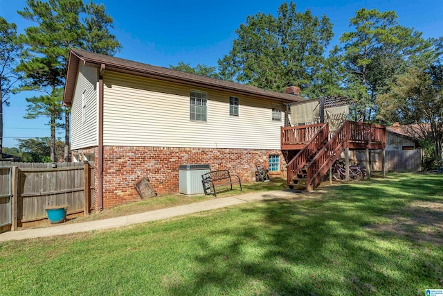 rear view of property featuring central air condition unit, a deck, and a yard