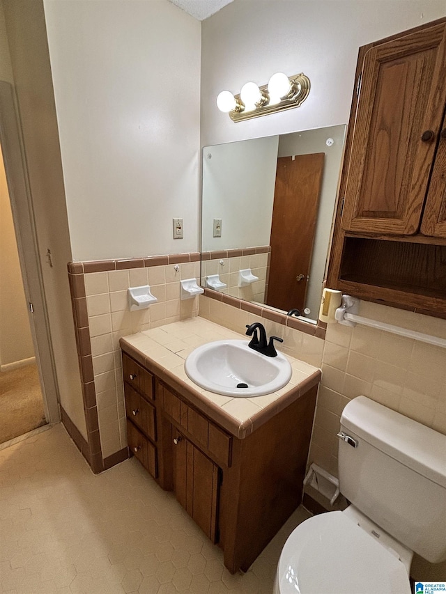 bathroom with tile patterned flooring, vanity, toilet, and tile walls